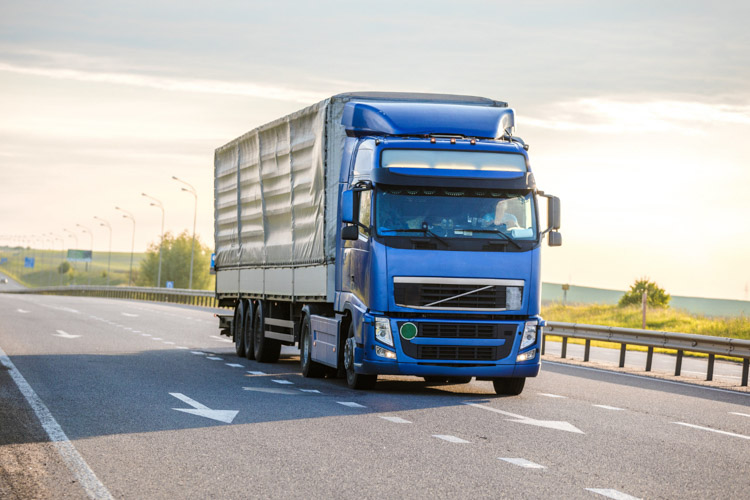 Μπλε φορτηγό κινείται σε μεγάλο δρόμο, έχοντας αυξημένη απόδοση μέσω επαναπρογραμματισμού εγκεφάλου (truck ECU remapping).
